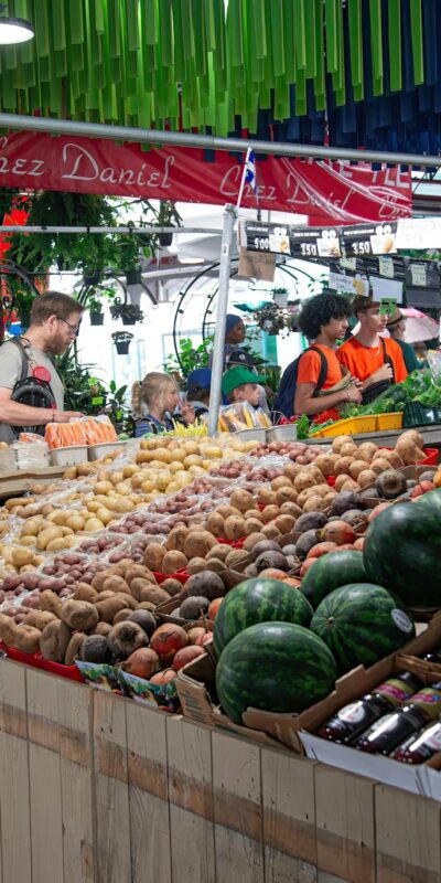 A bustling indoor market with diverse produce and shoppers creating a vibrant atmosphere.