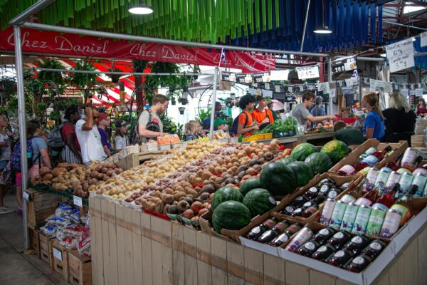 A bustling indoor market with diverse produce and shoppers creating a vibrant atmosphere.