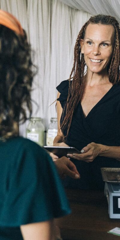 A woman assists a customer with a reusable container at a zero waste store, promoting sustainable shopping.