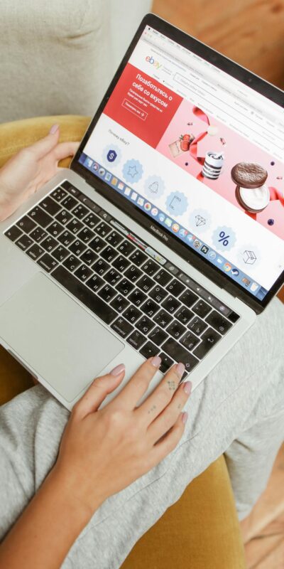 A woman sits comfortably indoors, browsing an online shopping website on her laptop.