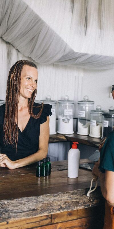 Smiling shopkeeper and customer at eco-friendly zero waste store counter.