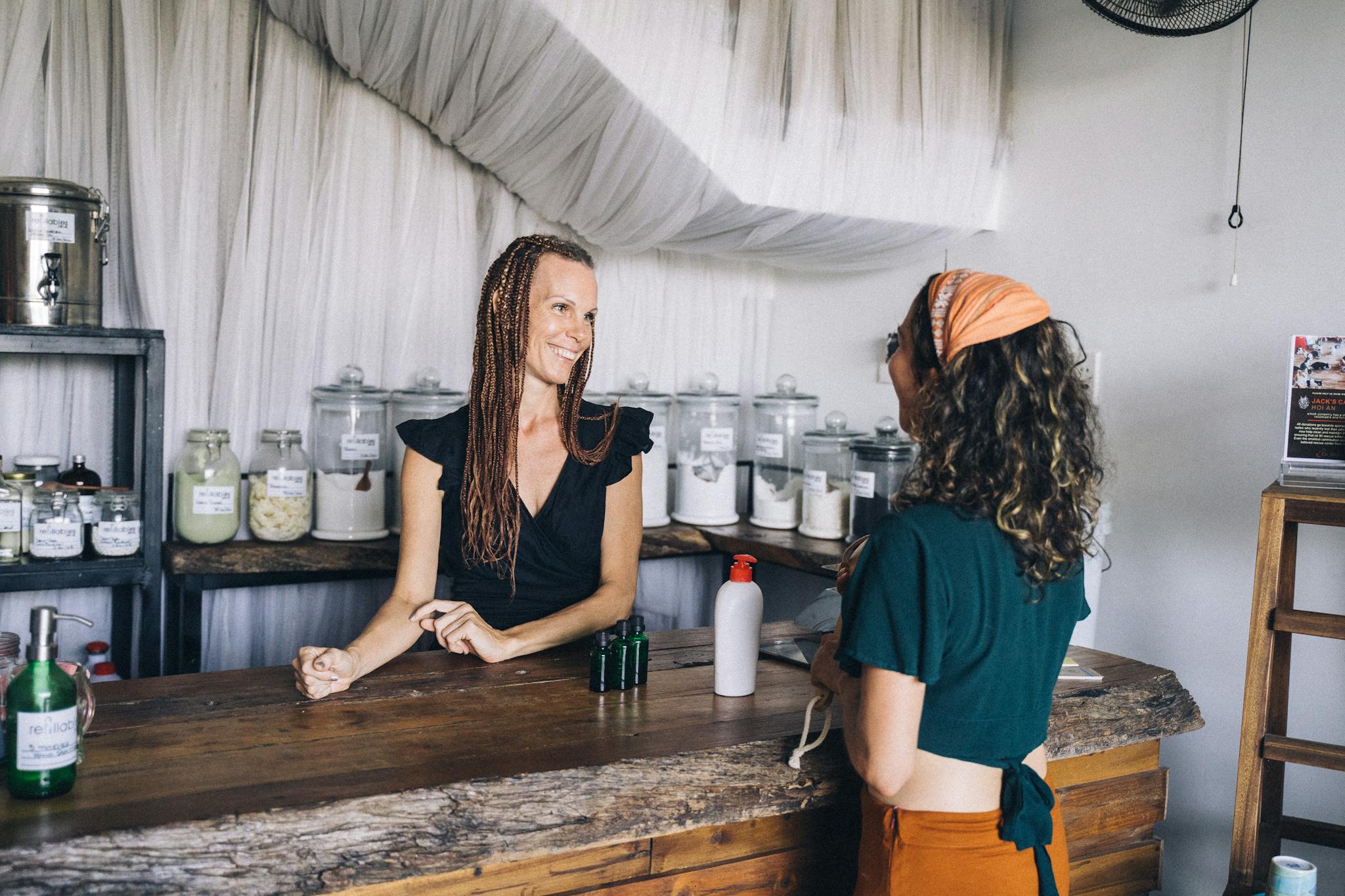 Smiling shopkeeper and customer at eco-friendly zero waste store counter.
